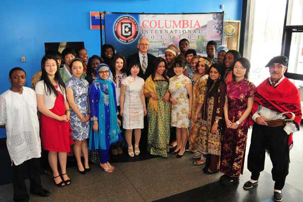 A group of diverse students and staff dressed in their culture's traditional clothing.